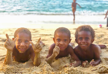 砂浜で寝そべる外国の子供達